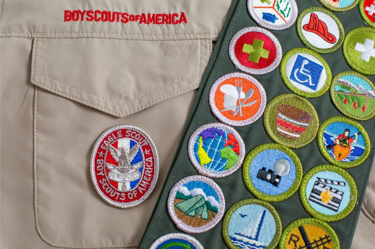 A merit badge sash beside a Scout uniform shirt with an Eagle patch